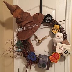 a harry potter wreath with an owl and other items on the front door for halloween