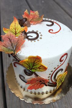 a cake decorated with fall leaves on a table