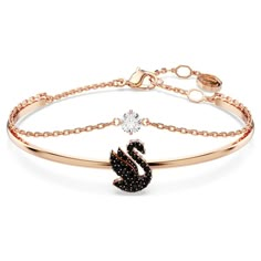 Adorn your wrist with the beauty of Swarovski’s signature emblem. This rose gold-tone plated jewelry features a rigid band with an elegant swan motif, expertly decorated with a pavé of jet black Swarovski ReCreated™ crystals. A secondary chain is also attached with a clear Swarovski Zirconia at the center. Intense yet radiant, this bangle is a perfect way to inject your style with intrigue. Swarovski Swan, Swarovski Bracelet, The Bangles, Jewelry Accessories Ideas, Elegant Bracelet, Swarovski Jewelry, Girly Jewelry, Metal Bracelets, Black Rose