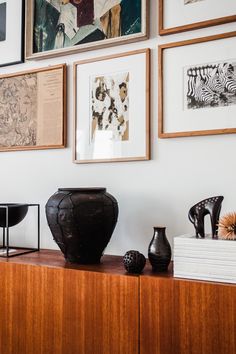 a wooden shelf with vases and pictures on the wall