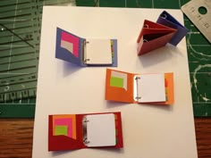 three binders are sitting on top of a cutting board with paper attached to them