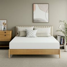 a white bed sitting next to a wooden dresser in a room with beige carpeting