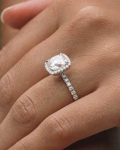 a woman's hand with a diamond ring on top of her finger and an engagement band