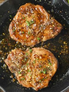 two pork chops cooking in a skillet