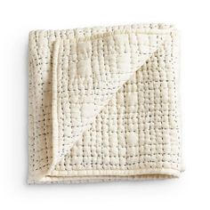 a white quilted blanket folded on top of each other with small black dots in the middle