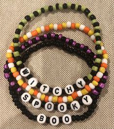 three bracelets with words written in different colors and sizes on each beaded strand