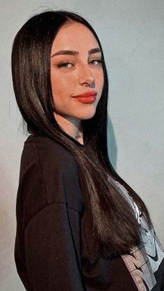 a woman with long dark hair wearing a black shirt and red lipstick on her lips