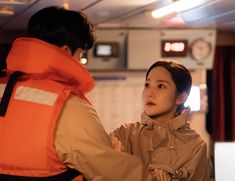 a woman standing next to a man in an orange life jacket