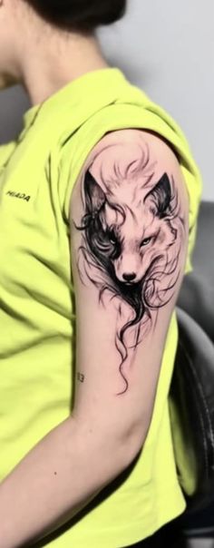 a woman with a wolf tattoo on her arm and shoulder, sitting in a chair