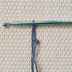 a green crochet hook with blue yarn on it