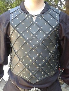 a man wearing a black leather vest with silver studs