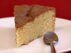 a piece of cake sitting on top of a white plate next to a silver spoon