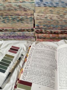 an open book sitting on top of a bed next to a pile of papers and markers