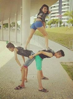 three people standing on top of each other while one person is balancing them over the other