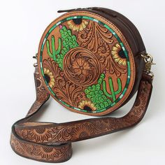 a brown leather purse with green and yellow designs on it's front strap, sitting on a white surface