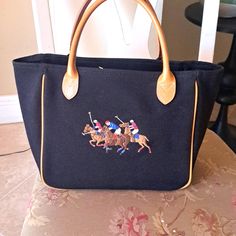 Ralph Lauren Beautiful Embroidered Canvas And Leather Eqestrian Motif Shopping Tote In Navyblue. Beautifully Embriodered Polo Game Scene On Canvas And Leather Tote. Leather Handles And Trim. Zipper Onside Compartment And Two Slip Pockets. Beautiful Like New Condition. Measurements: Height 9inches, Width 5. 75inches, And Length Flatlay Is 14inches, Length 10inches. **** Today Sale$200 Polo Game, Ralph Lauren Equestrian, Pony Games, Ralph Lauren Bags, Polo Pony, Embroidered Canvas, Leather Handles, Shopping Tote, Leather Handle