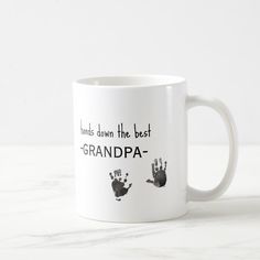 a white coffee mug with two hand prints on it that says, hands down the best grandpa