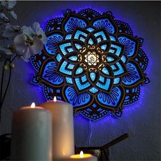 two candles are lit next to a wall decoration