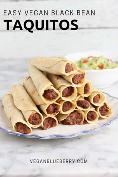 several burritos stacked on a plate next to a bowl of guacamole