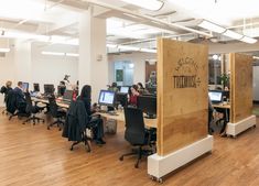 an open office with people working on their computers and sitting at desks in front of them