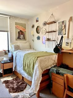 a bed room with a neatly made bed next to a desk and guitar on the wall