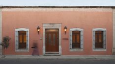 a person walking past a pink building with two doors and three windows on the side