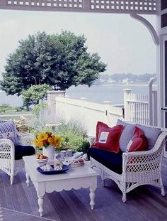 an image of a porch with furniture and flowers on the table in front of it