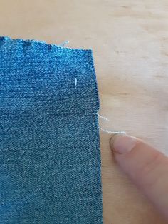 someone is stitching the side of a piece of blue fabric with white thread on it