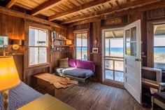 a living room with wood paneling and lots of windows on the side of it