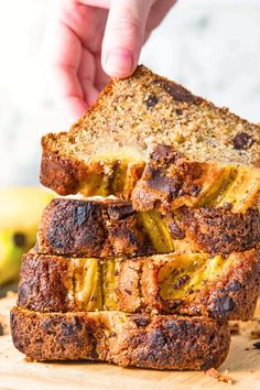 someone is picking up some fruit bread from the stack on top of each other, with bananas and raisins in the background