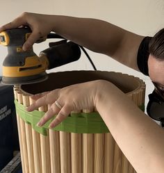 a woman is sanding the bottom of a basket with an electric sander on it