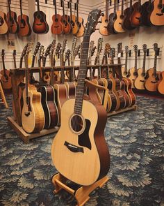 an acoustic guitar is on display in a music store, with other guitars behind it