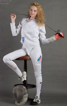 a woman sitting on top of a chair holding an object in her hand and posing for the camera