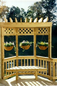 a wooden gazebo with flowers hanging from it