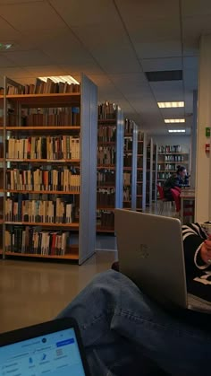 a man sitting in front of a laptop computer on top of a desk next to a book shelf filled with books