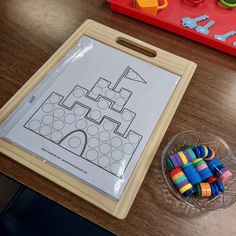 a cutting board with some colored crayons next to it on a wooden table