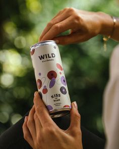 a woman is holding a can of wild wine in her hands while another person holds it