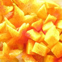 chopped up yellow and red fruit on a white plate with seasoning sprinkles