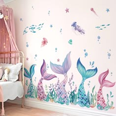 a child's room decorated in pink and blue with mermaid tails on the wall