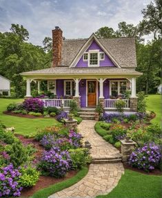 a purple house with lots of flowers in the front yard and steps leading up to it