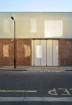 an empty street in front of a building with two doors on the side of it