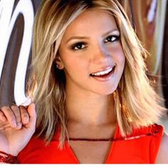 a close up of a person wearing a red shirt and smiling at the camera with her hand on her hip