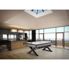 a pool table in the middle of a room with large windows and wooden flooring