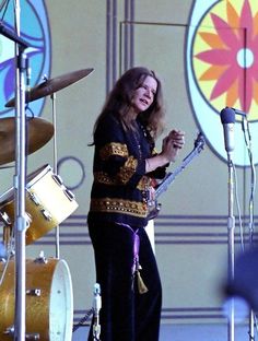 a woman standing on top of a stage next to drums