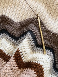 a crocheted blanket with a knitting needle resting on it