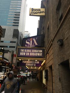 a man is walking down the street in front of a sign for six on broadway