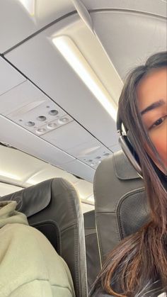 a woman wearing headphones sitting in an airplane