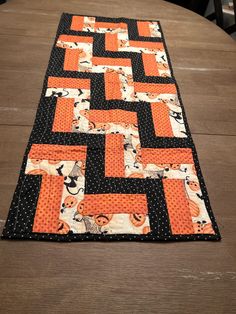 an orange and black table runner on top of a wooden table