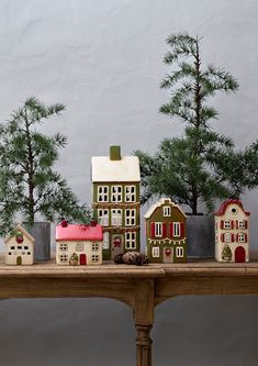 a wooden table topped with miniature houses and trees