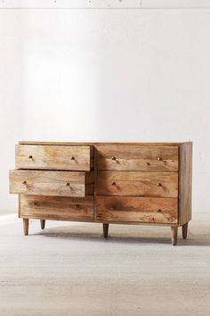 a wooden dresser sitting on top of a hard wood floor next to a white wall